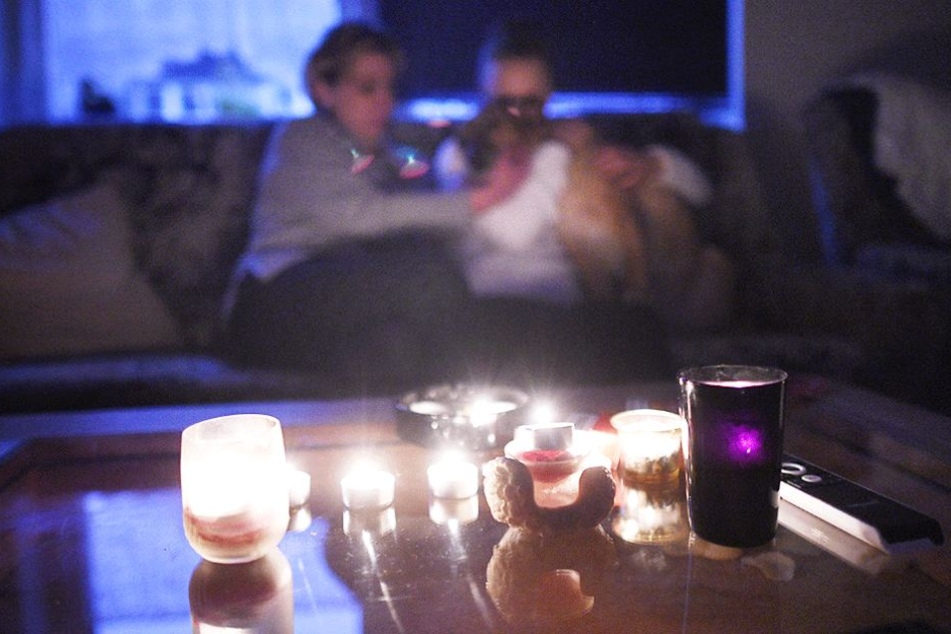 Strom abgedreht: Eine Mutter sitzt mit ihrem Sohn in einer mit Kerzen beleuchteten Zimmer.