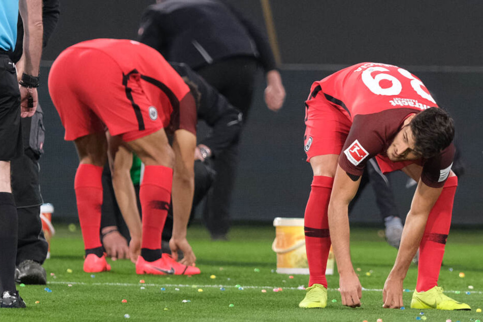 Verspätete Eier-Suche kurz nach dem Anpfiff. Aus Protest gegen die Montagsspiele warfen die Zuschauer bunte Ostereier aufs Feld. Auch Eintracht-Stürmer Goncalo Pacienca (Re.) half beim Aufsammeln.