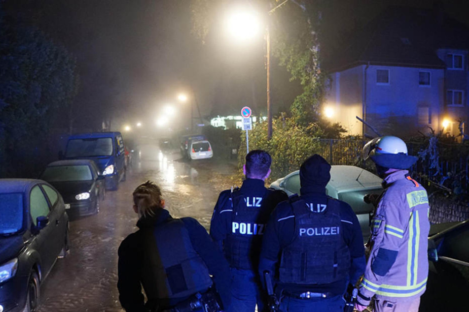 Polizei und Feuerwehr blicken auf den gefluteten Ostburger Weg.
