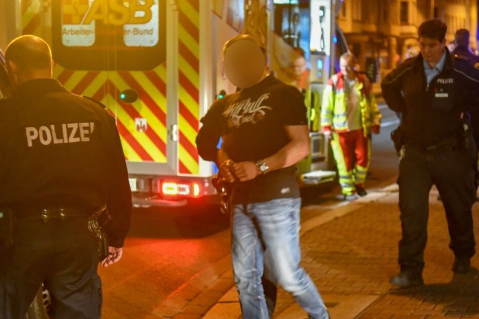 Einer der mutmaßlichen Täter wird von Beamten abgeführt.