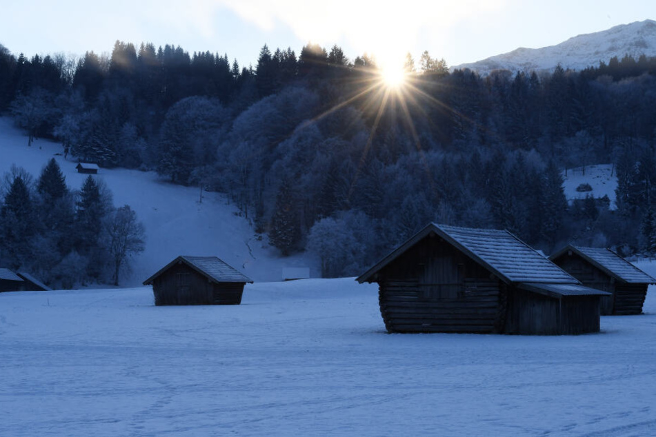 Die Sonne geht hinter einer typischen Kulturlandschaft des Werdenfelserlandes auf.