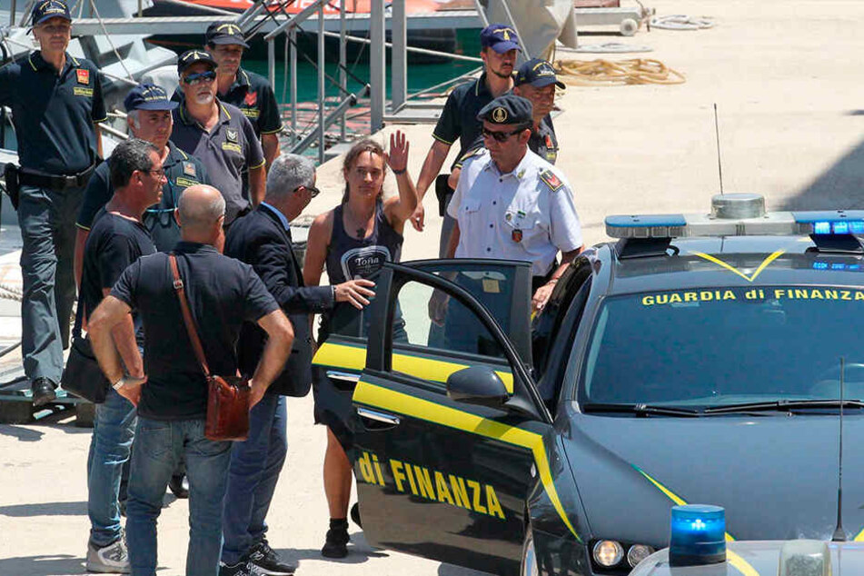 Carola Rackete (Mi.) steigt nach ihrer Ankunft im Hafen von Porto Empedocle in ein Polizeiauto.
