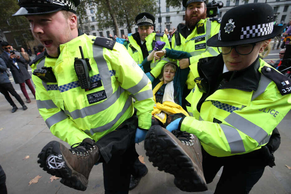 Polizisten tragen eine Extinction Rebellion Demonstrantin von einer Londoner Blockade.
