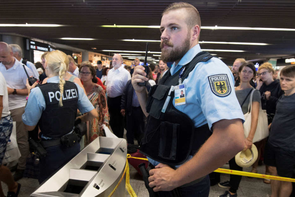 Polizisten und Passagiere stehen in Halle A im Terminal 1 des Flughafens Frankfurt.