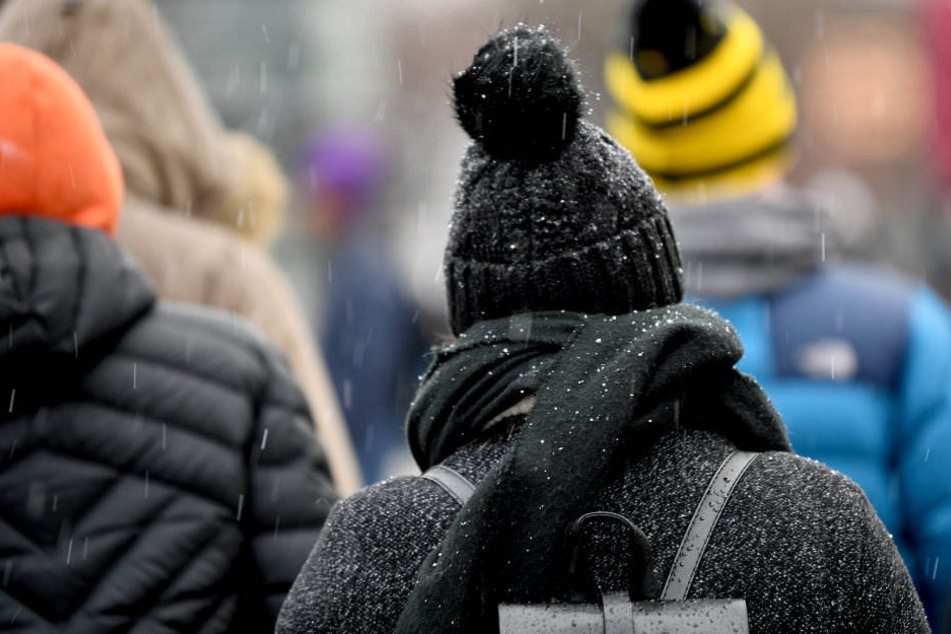 Schneeregen fällt auf Spaziergänger.