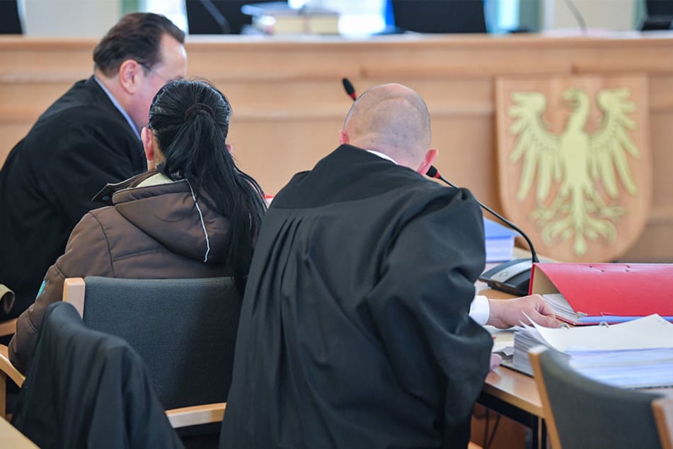 Die Angeklagte sitzt in einem Verhandlungssaal des Landgerichts zwischen Anwälten.