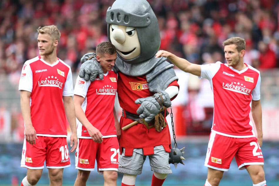 Unions Spieler Sebastian Andersson (l.), Grischa Prömel (m.) und Christopher Lenz (r.) freuen sich über den 2:0-Sieg gegen den HSV mit Maskottchen Ritter Keule.