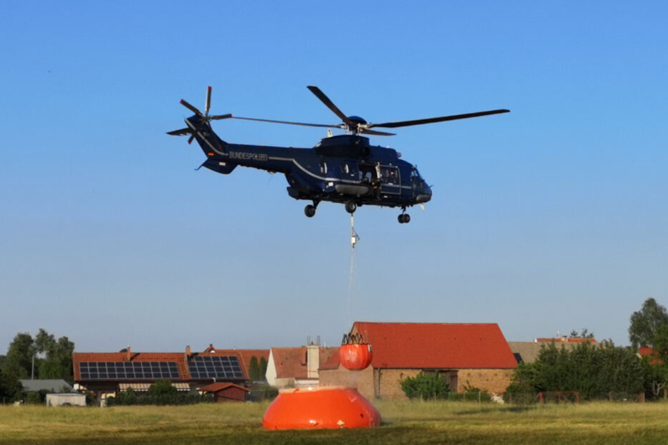 Ein Hubschrauber der Bundespolizei nimmt mit einem Löschwasser-Außenlastbehälter nahe Jüterbog Wasser auf.