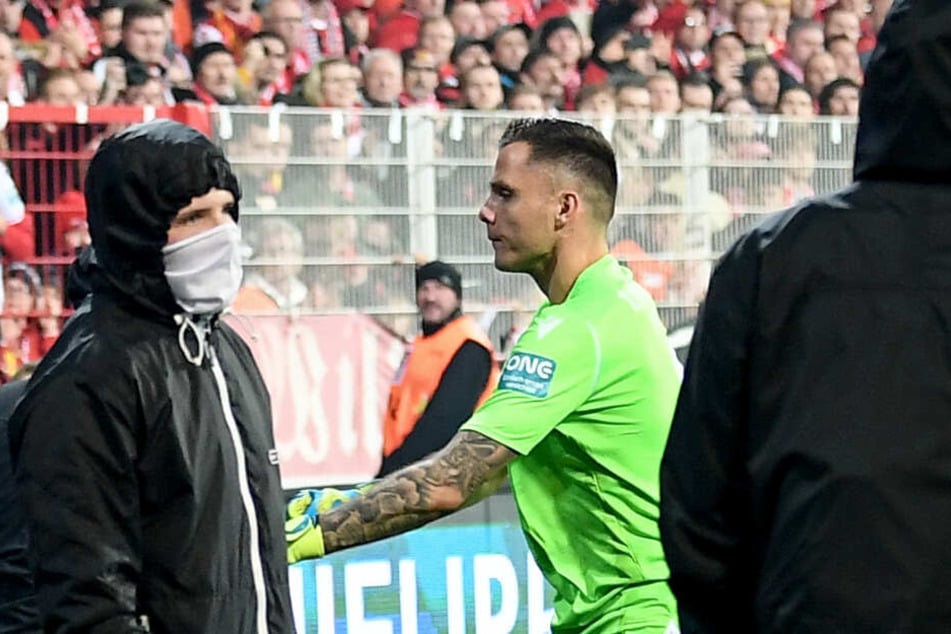 Unions Rafal Gikiewicz (M) beruhigt vermummte Fans seines Vereins, nachdem Hertha-Fans Pyrotechnik auf das Spielfeld geschossen (Symbolbild).