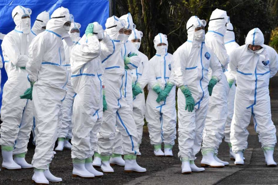 In Schutzanzügen gekleidete Menschen stehen im japanischen Gifu.