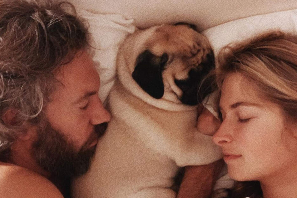 Charlotte, ihr Freund Felix und Mops Mimi liegen gemeinsam im Bett.
