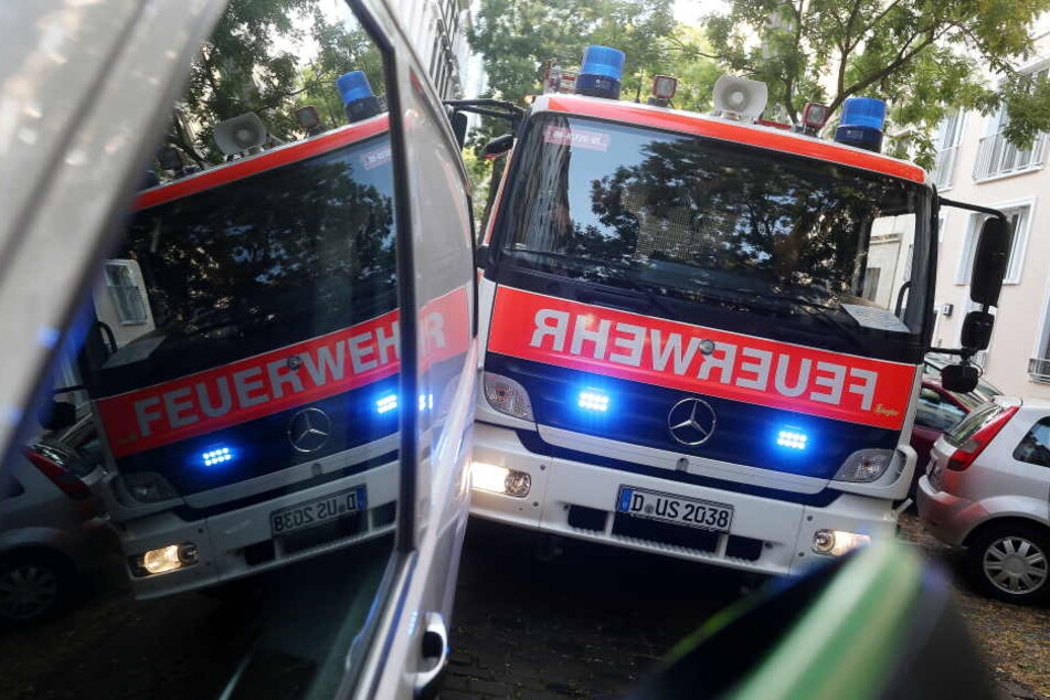 Ein durch einen Falschparker blockiertes Feuerwehrauto mit Blaulicht spiegelt sich in den Scheiben des Falschparkers