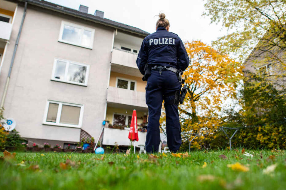 Im Garten des Abwesens steht eine Polizeibeamtin.