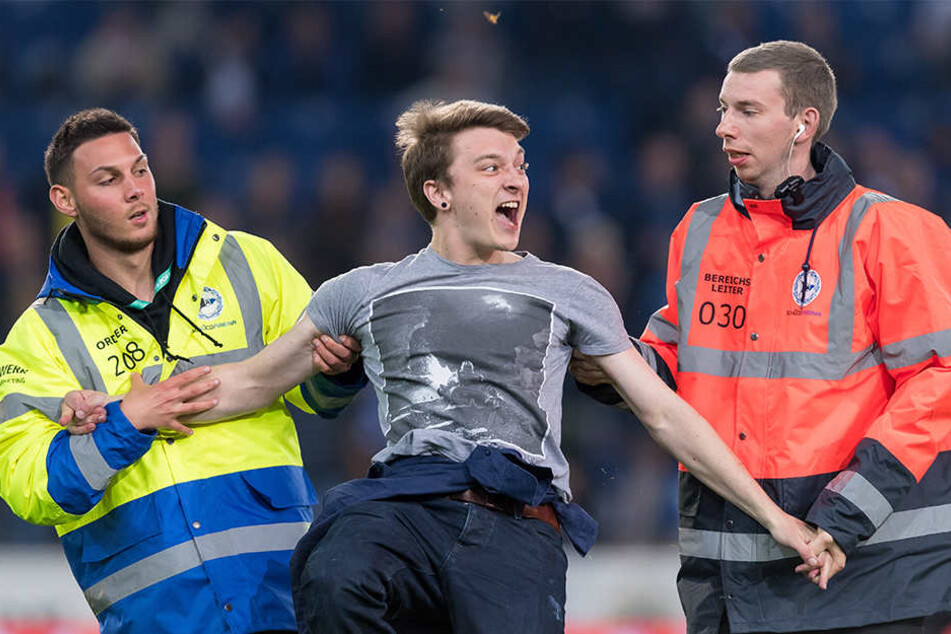 Der Fan lief aufs Feld und musste von Ordnern abgeführt werden.