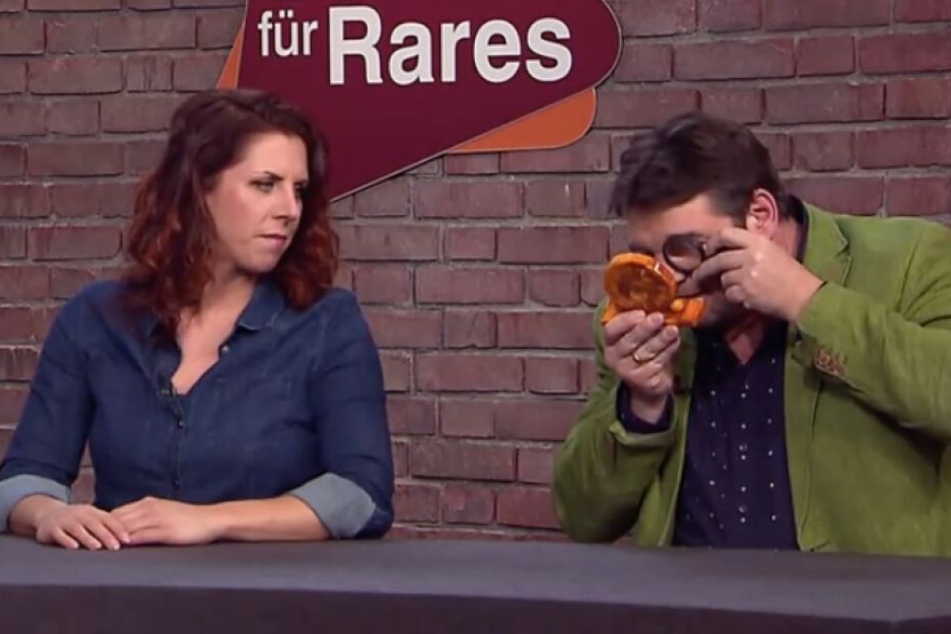 Die Händler haben die Bernsteinuhr genau untersucht.