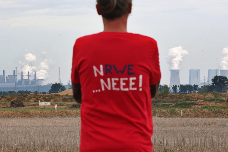 Ein Demonstrant am Randes des Tagebaus Hambach vor der Kulisse des RWE Braunkohlekraftwerks. (Symbolbild)