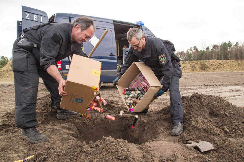 Die Kriminalhauptkommissare kippen kistenweise beschlagnahmte Pyrotechnik in das Böller-Grab.