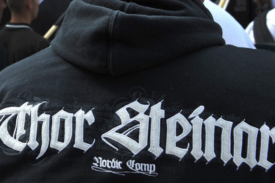 Mit Kleidung der Modemarke Thor Steinar ist ein Mann während einer Kundgebung bekleidet. (Archivbild)