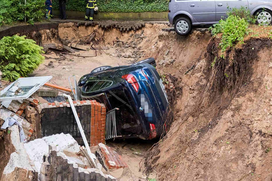 In Hamburg-Lohbrügge liegt das Auto in einer Senke, die nach heftigem Regen entstanden ist.