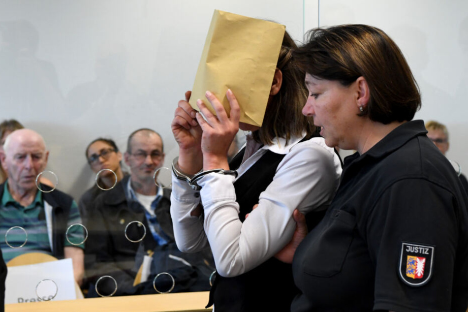 Die Angeklagte verdeckt ihr Gesicht zu Prozessbeginn.