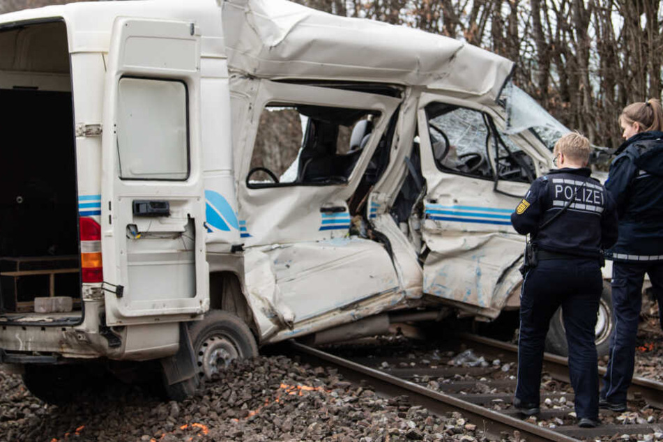 Polizisten stehen vor dem Wrack eines Transporters.