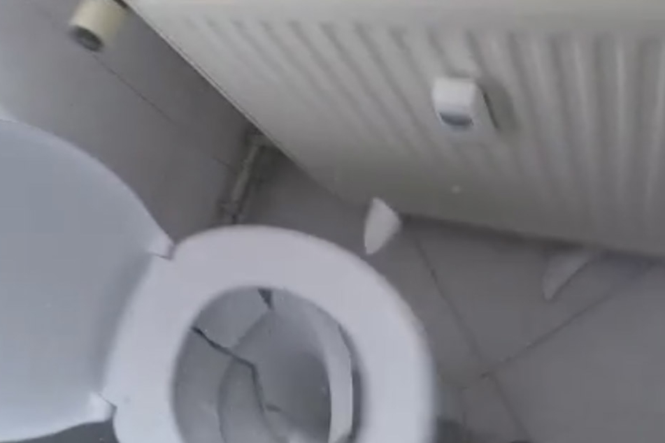 Mit einem Hammer zertrümmern sie das ganze Klo.