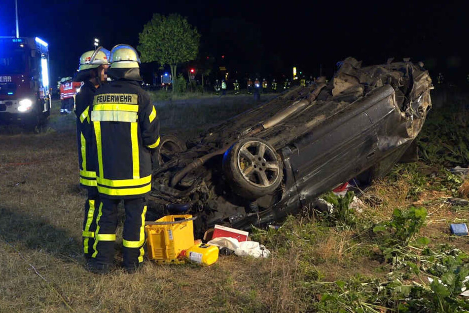 Das Wrack des Autos wird von Feuerwehrmännern begutachtet.