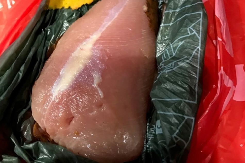 Graues Pulver wurde in kleine Löcher eines rohen Stücks Hühnerbrust gestopft.