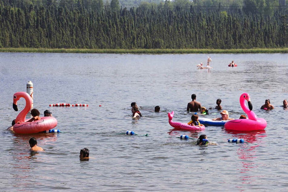 Baden statt Bibbern. Kinder spielen mit aufblasbaren Flamingos und schwimmen am Goose Lake.