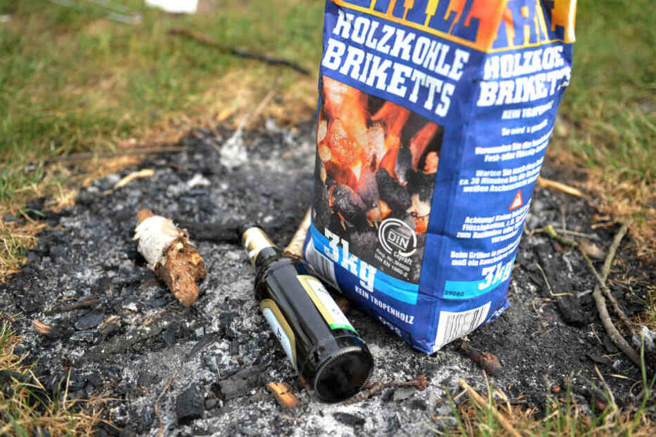 Eine leere Flasche Bier und ein Sack Grillkohle liegen am Freitag am Unisee in Bremen auf einer verkohlten Stelle.