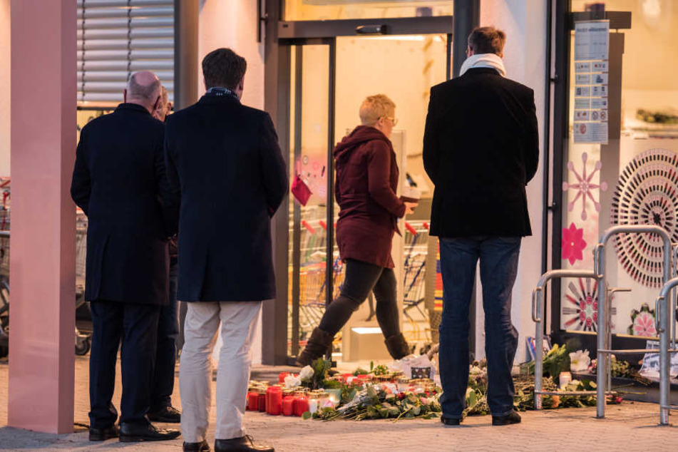 In einer Drogeriemarktfiliale in Kandel wurde die 15-Jährige erstochen. Nach der Tat trauern Menschen vor dem Laden.