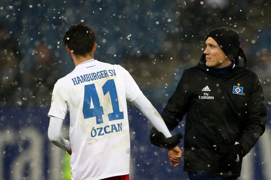 Am 19. Spieltag im Volksparkstadion stehen Hamburgs Berkay Özcan (links) und Trainer Hannes Wolf nach dem Spiel auf dem Platz, während es schneit.