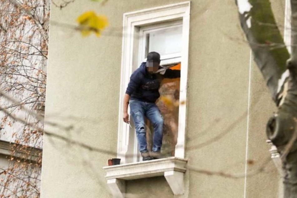 Der Mann steht im Fenster, in seiner rechten Hand hält er ein Messer.
