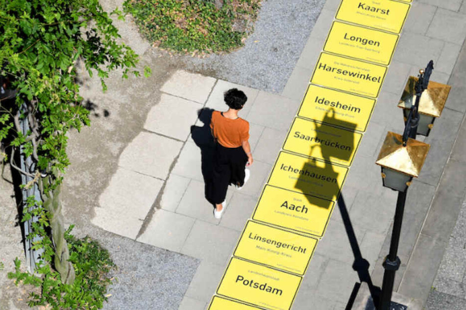 Die gelben Ortstafeln werden probeweise auf einem Berliner Gehweg ausgelegt.