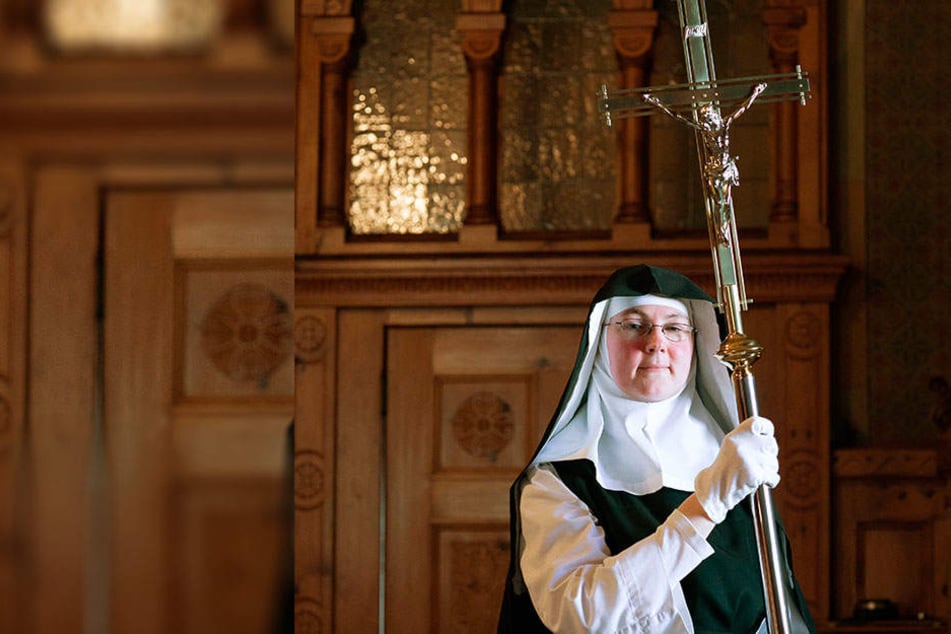 Für die Osternacht bringt die Ordensfrau das Prozessionskreuz aus der Sakristei in die Kirche.