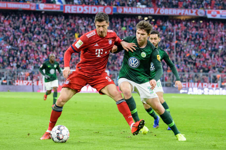Robert Lewandowski vom FC Bayern München (l) und Elvis Rexhbecaj vom VfL Wolfsburg im Zweikampf um den Ball.