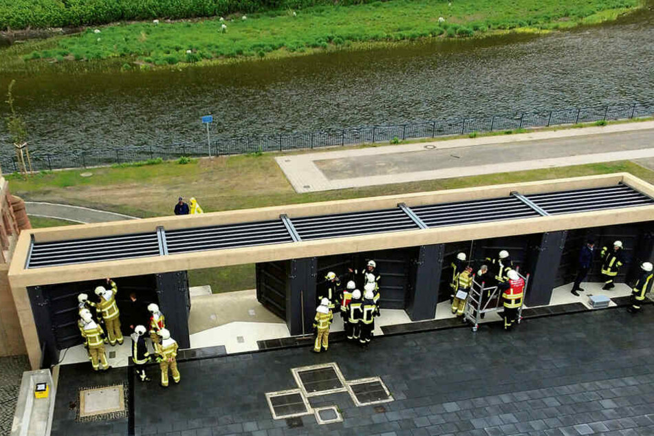 Bei der Hochwasserübung in Grimma schließen Feuerwehrleute die fünf Tore an der erst kürzlich fertiggestellten Pergola am Gymnasium.