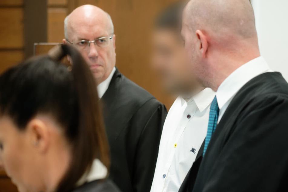 Der Angeklagte steht umgeben von seinen Anwälten Jordana Wirths, Christof Miseré und Martin Bücher (r) im Landgericht in einem Saal.