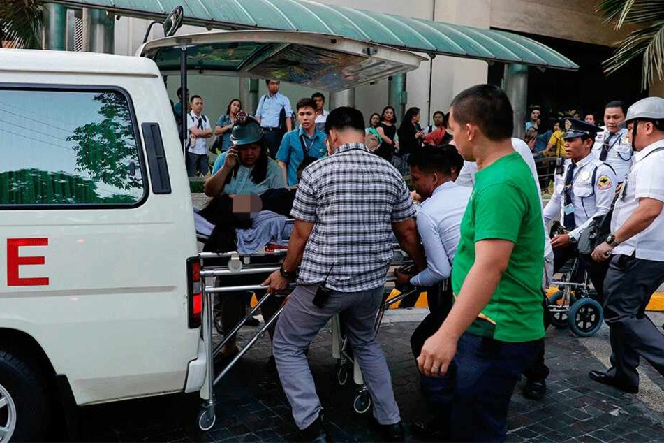 Manila: Rettungskräfte tragen eine Frau zu einem Krankenwagen, nachdem ihr schwindlig wurde.