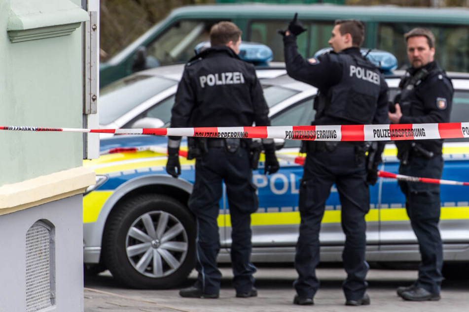 Polizeibeamte stehen vor einem Gebäude in Flensburg, in dem zuvor eine eine tote Frau entdeckt wurde.