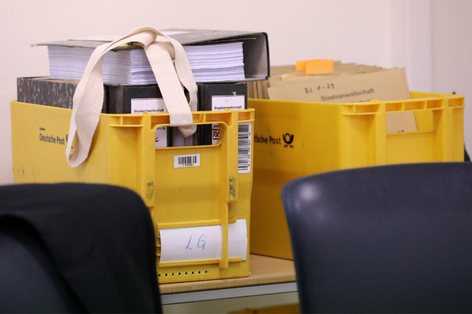 Vor Beginn des Prozesses wegen Mordes durch Unterlassen und Misshandlung von Schutzbefohlenen in sieben Fällen stehen Akten in gelben Post-Kisten hinter dem Richtertisch.