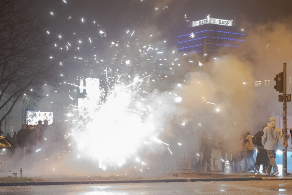 Böller und Raketen steigen auf der Straße an der Oberbaumbrücke in die Luft, während Passanten vorbeigehen.