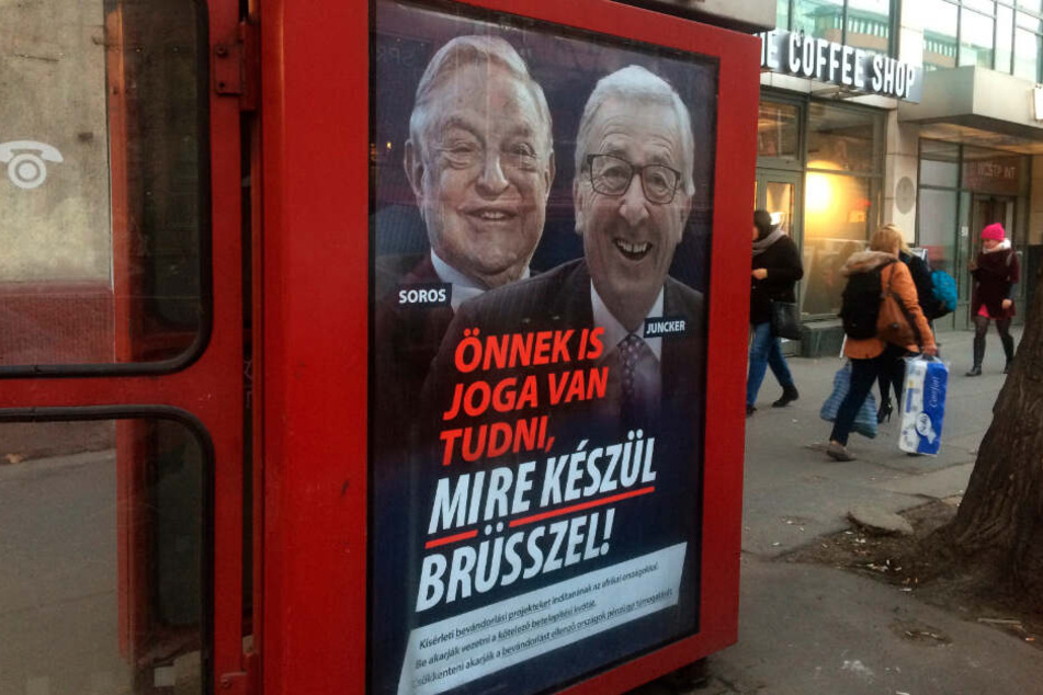 An einer Telefonzelle in Budapest hängt ein Plakat mit dem ungarisch-amerikanischen Milliardär George Soros und dem Präsidenten der EU-Kommission Jean-Claude Juncker mit der Aufschrift "Sie haben ein Recht darauf zu wissen, was Brüssel vorhat".