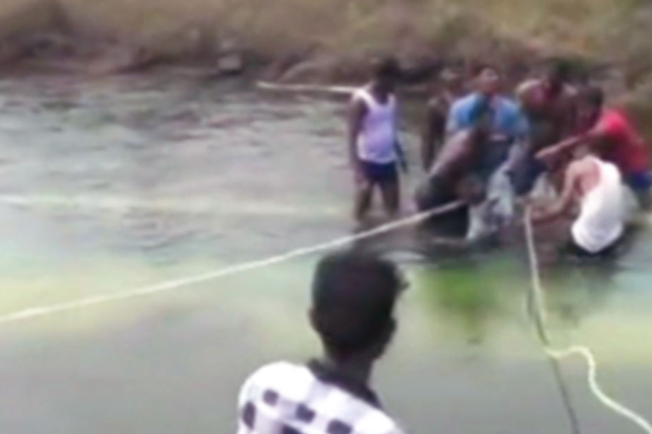 Hier versuchen Helfen, den Bus mit den Schulkindern aus dem Wasser zu ziehen.