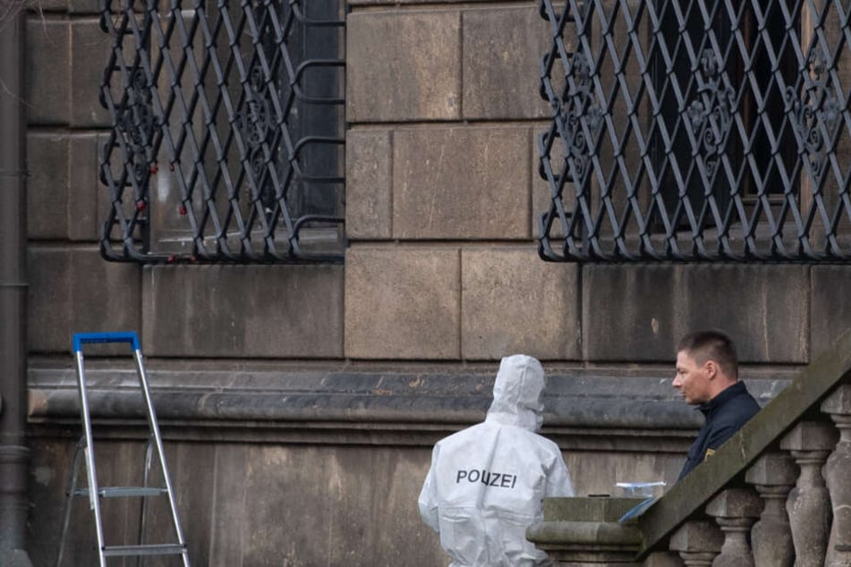 Einsatzkräfte der Polizei neben dem durchtrennten Gitterfenster.