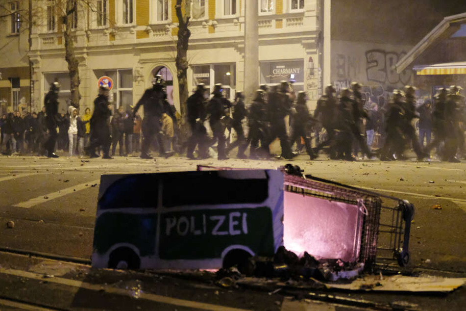 Ein Einkaufswagen mit einem gebastelten Polizei-Auto aus Pappe - die Randalierer sollen den brennenden Wagen in eine Gruppe Polizisten geschoben haben.