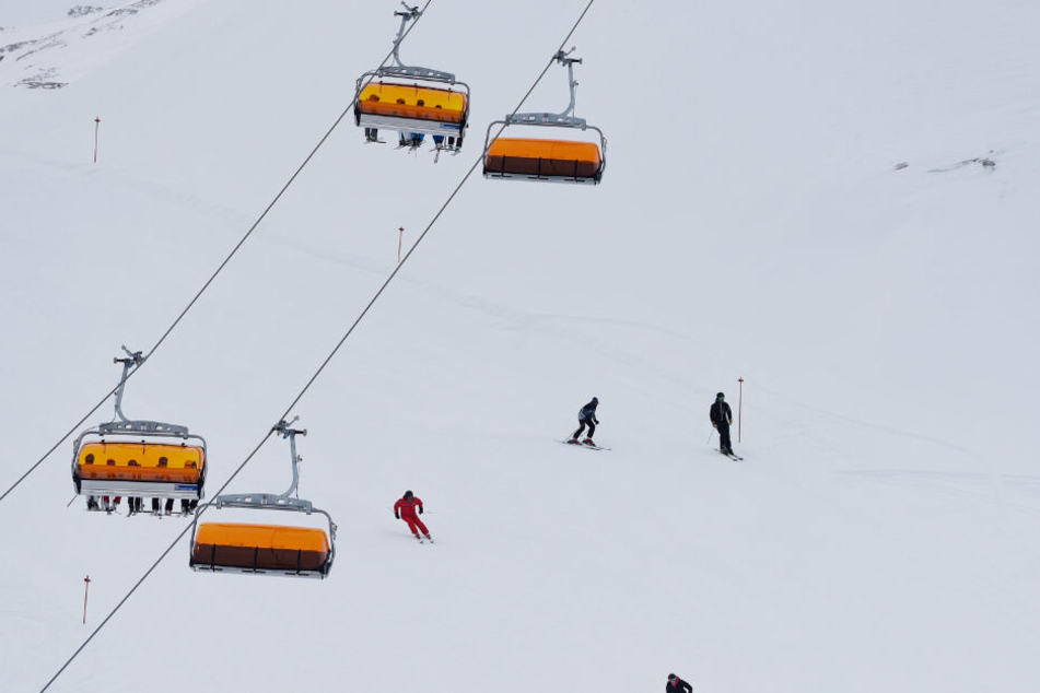 Skifahrer fahren in Garmisch-Partenkirchen im Skigebiet Zugspitze auf der Piste unter einem Sessellift entlang.