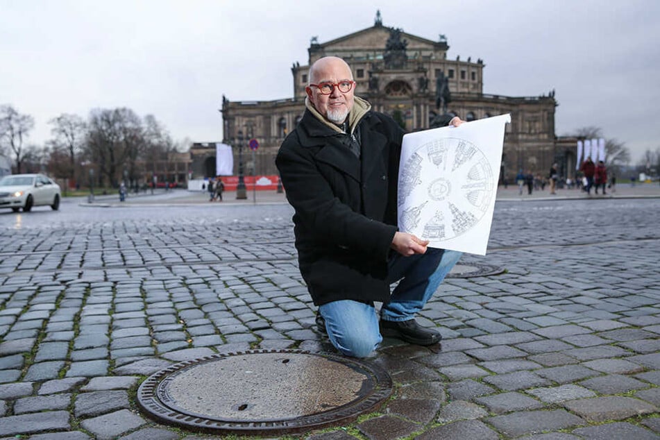 Künstler Peter Scharfe (56) zeigt einen der Deckel, der noch ausgetauscht wird. Die Semperoper im Hintergrund wird dann auf dem Gully verewigt.