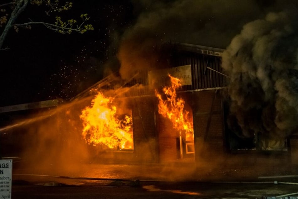 Flammen schlagen aus Fenstern und Türen des Gebäudes.