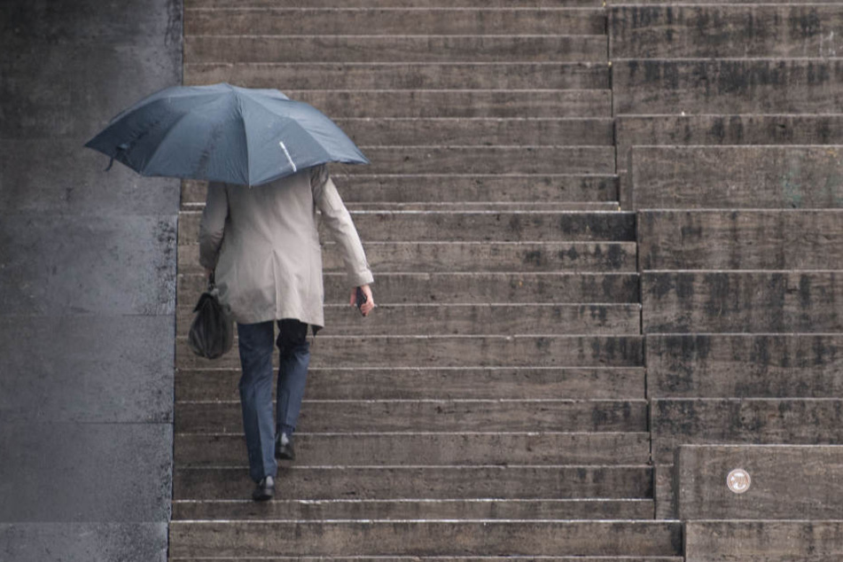 Ein Mann geht die Treppen auf dem Schlossplatz in Stuttgart bei Regen hoch. Regen sorgt für den Anstieg des Wasserstands im Rhein.